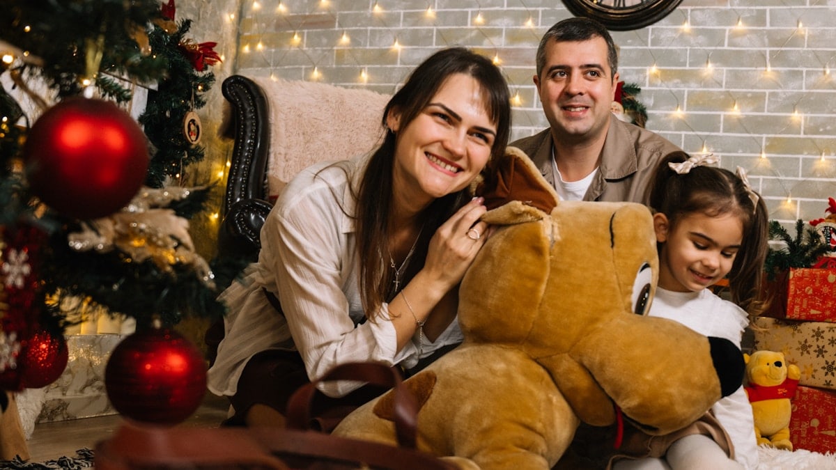 A man and a woman sitting on a couch with a child and a teddy bear